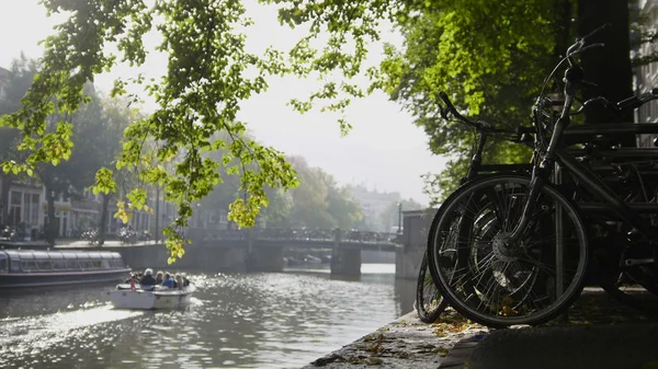 Вид на колесный велосипед на амстердамском канале, рядом плавает экскурсионная лодка, солнечная европейская осень — стоковое фото