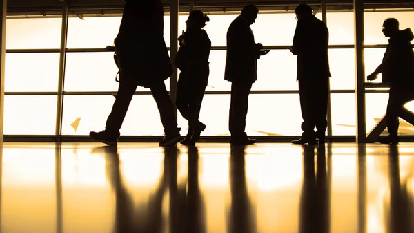 Utasok kövesse a beszállás előtt ablak airport, silhouette, meleg poggyásszal — Stock Fotó