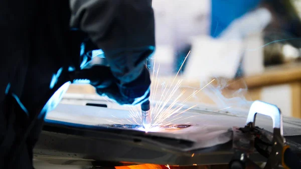 Welding industrial: worker repair detail in car service, close up