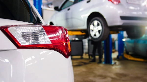 Servicio de coche - retroiluminación roja de auto blanco en el automóvil levantado opuesto — Foto de Stock