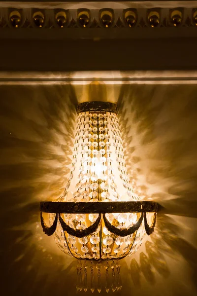 Luxury chandelier on wall in golden ballroom, close up — Stock Photo, Image