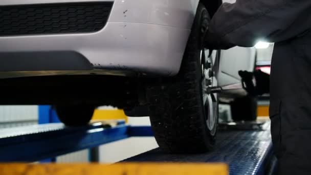 Csavarja pin autó kerék az autó a garázsban, autószerelő csúszka — Stock videók
