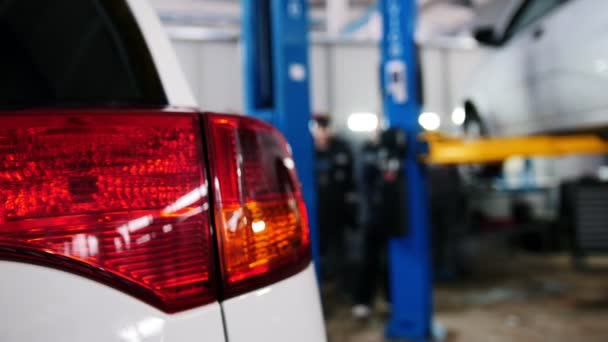Auto details - rode auto koplamp close-up in Diagnostische service - monteur in de buurt van opgeheven auto werken — Stockvideo