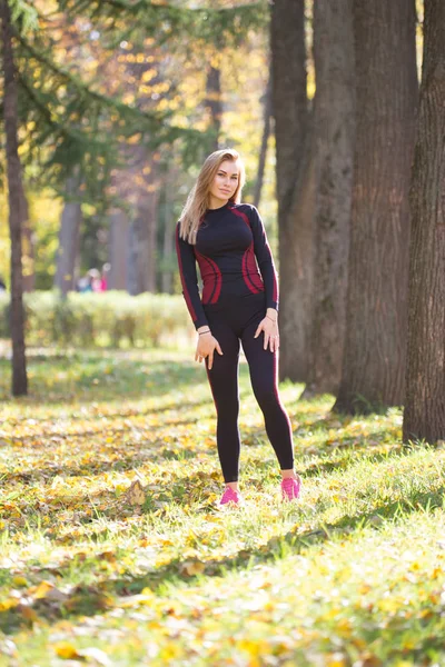 Mladí fitness krásy dívka během cvičení stojící poblíž stromy na podzim park — Stock fotografie