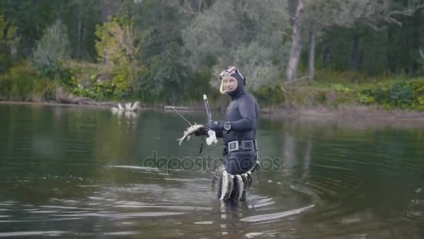 Spear fisherman out of the water and shows Freshwater Fish at spear of underwater fisherman after hunting in forest river — Stock Video