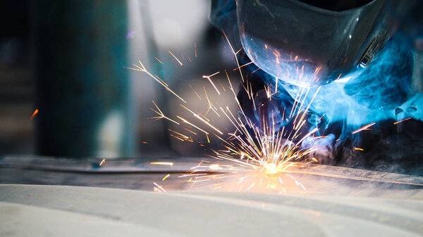 Industrial concept: worker in helmet repair detail in car auto service, close up