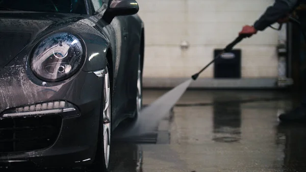 Arbeiter im Autoservice wäscht mit Wasserschläuchen ein Luxusauto im Sud — Stockfoto