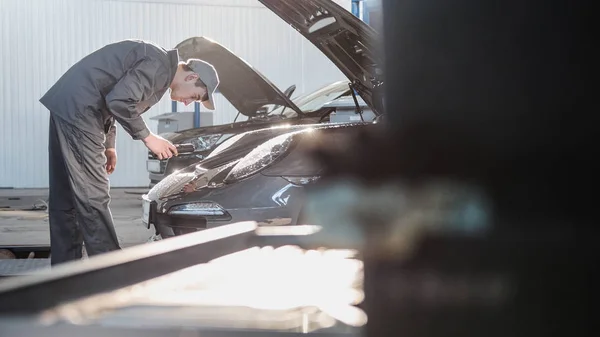Mecánico en el garaje del automóvil que comprueba el capó para el coche deportivo de lujo — Foto de Stock