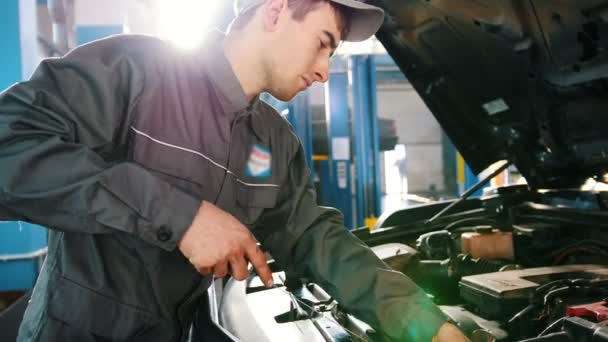 Mekaniker i overaller kontrollerar nivån av motorolja i bilen - bil service reparera — Stockvideo
