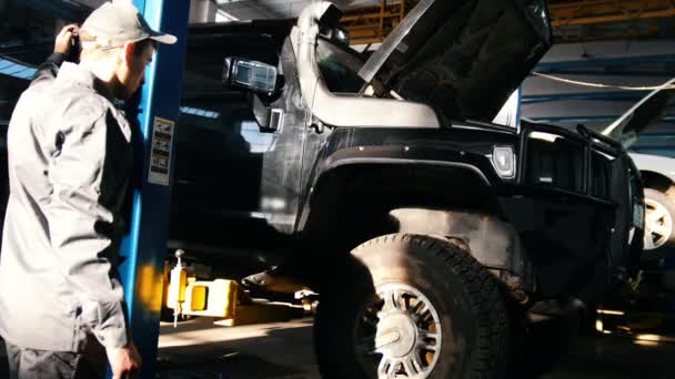 Механик поднимает внедорожник в гаражном автомобильном сервисе — стоковое видео