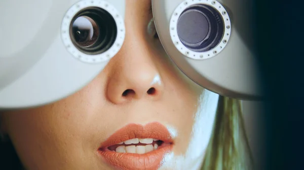Jovem com lábios vermelhos verifica os olhos no equipamento moderno no centro médico — Fotografia de Stock