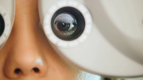 Jovem com lábios vermelhos verifica os olhos no equipamento moderno no centro médico, macro — Fotografia de Stock