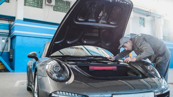 Mecánico en el garaje del coche que comprueba la capucha del deportivo de lujo — Foto de Stock