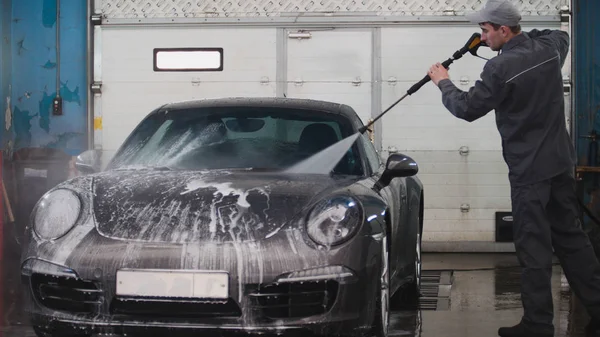 Mecánico en el servicio de coches es el lavado de coches deportivos en las suds por mangueras de agua — Foto de Stock