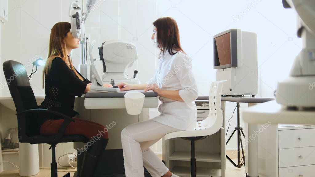 Modern ophthalmologist examining attractive womans eyes with modern equipment