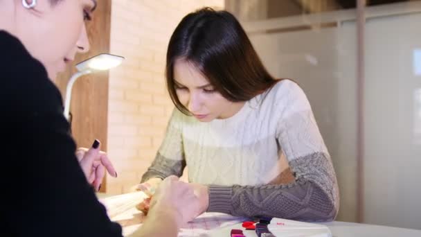 Девушка выбирает цвет и текстуру ногтей в профессиональном салоне красоты маникюр, слайдер — стоковое видео