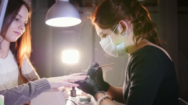 Soins professionnels des ongles en cours, cosmétique avec masque en gants noirs faisant des ongles client féminin pour une manucure avec couvercle en gel — Video