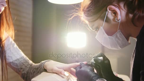 Профессиональный уход за ногтями в процессе, косметик с маской в черных перчатках делает ногти женский клиент для маникюра с гелевой крышкой, ползунок — стоковое видео
