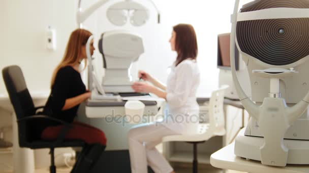 Modern ophthalmologist examining attractive womans eyes with modern equipment, blured — Stock Video