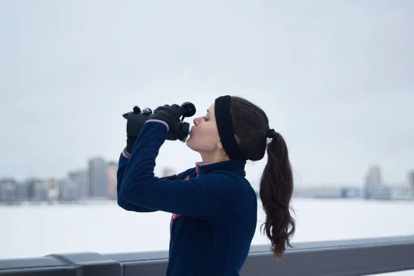 Sport kvinnliga dricker vatten på jogging utanför på molnig vinterdag — Stockfoto