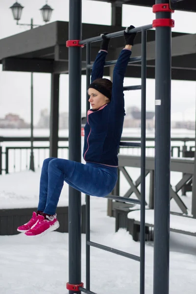 Jovem mulher do esporte fazendo exercícios de imprensa sobre o exercício de fitness no parque de inverno de neve — Fotografia de Stock