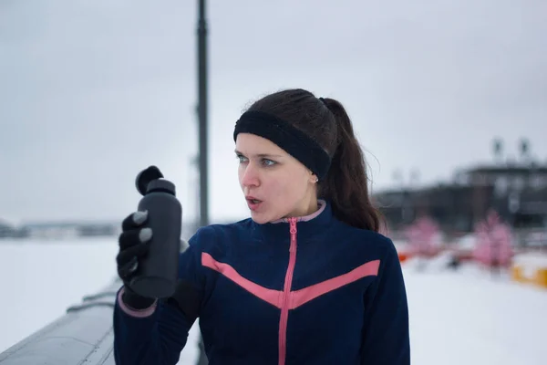 Sport kvinna trött efter löpning och drycker vatten utanför på molnig vinterdag — Stockfoto