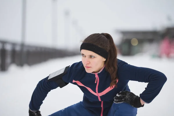 Kobieta runner wyciąganie nóg przed Uruchom przy promenadzie zima śnieg, zbliżenie — Zdjęcie stockowe