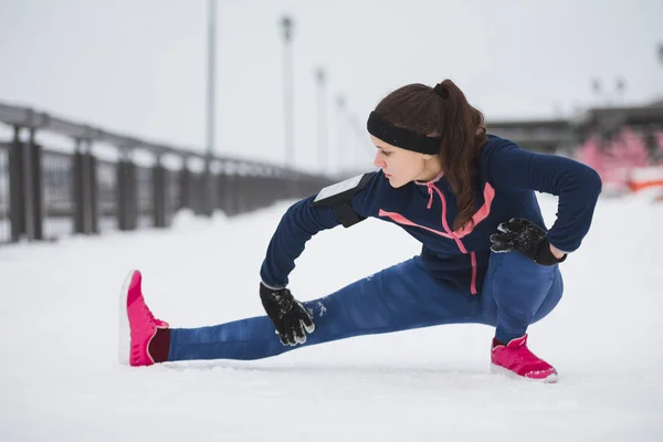 Kobieta runner wyciąganie nóg przed uruchomić przy promenadzie zima śnieg. Koncepcja fitness. — Zdjęcie stockowe