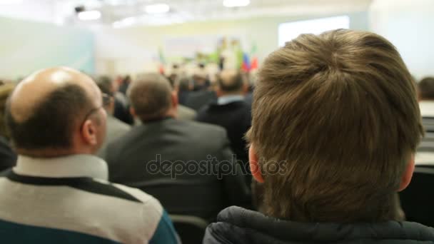 Собрание людей на конференции - сидя в зале и глядя на лепестки — стоковое видео