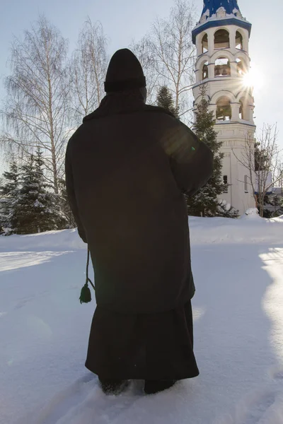 Nunna håller ett radband i händerna nära klocktornet i ortodoxa kloster, Ryssland — Stockfoto
