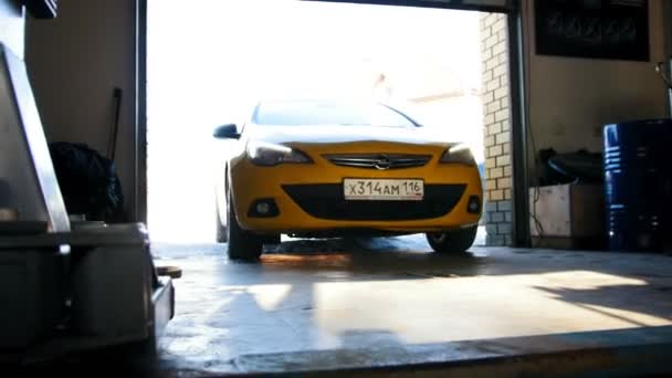 カザン、ロシア、1 マート 2017、車サービスの作業 - ガレージに黄色の車ドライブ — ストック動画