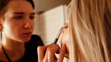 Makyaj sanatçısı yakışıklı modelleri göz makyaj fırça ile yapar.