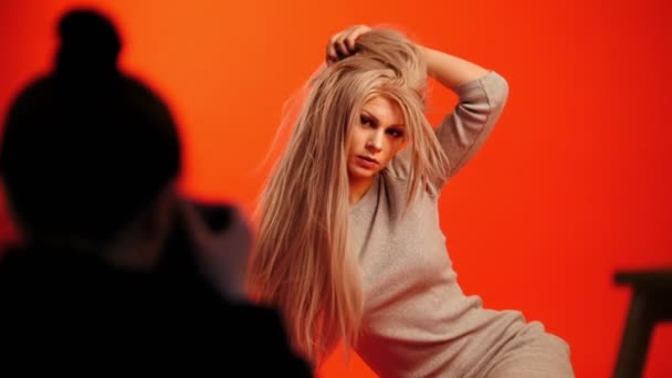 Tras bastidores: modelo femenina rubia posando para fotógrafo en estudio rojo — Vídeos de Stock