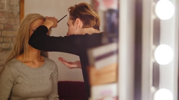 Visage - maquilladora y modelo rubia cerca del espejo en el vestidor — Vídeos de Stock
