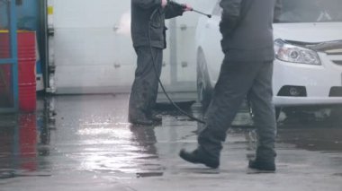 Oto yıkama - Oto Servisi işçi su hortumlar tarafından suds arabada yıkıyor