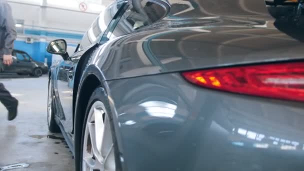 Автомобильный гараж - роскошный спорткар, стоящий для проверки и ремонта, вид сзади - раздвижной кадр — стоковое видео