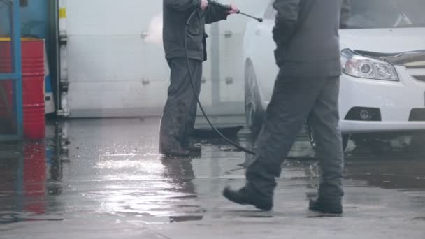 Lavage de voiture - travailleur en service automobile lave une voiture dans la mousse par des tuyaux d'eau — Video