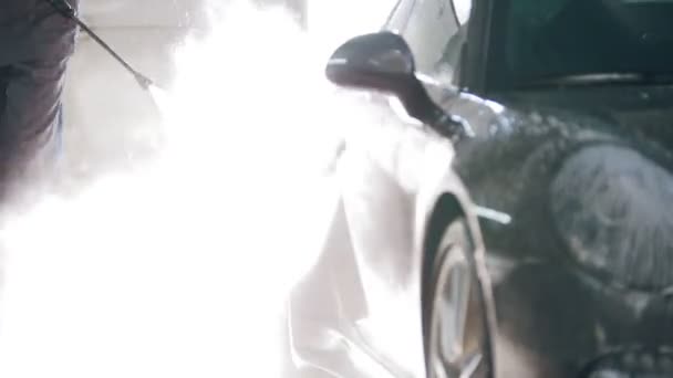 Travailleur dans le garage service automobile lave une voiture dans la mousse par des tuyaux d'eau — Video