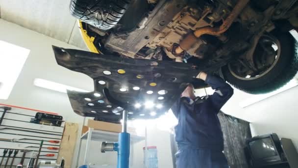 Mechanik zkontroluje spodní části vozidla v garáži automobilového provozu, zblízka — Stock video