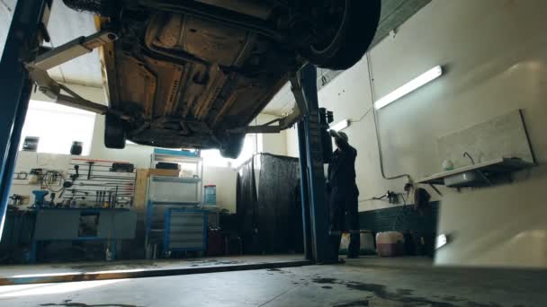 El coche se baja en el servicio de automóvil para la comprobación, detalle de las reparaciones del trabajador — Vídeos de Stock