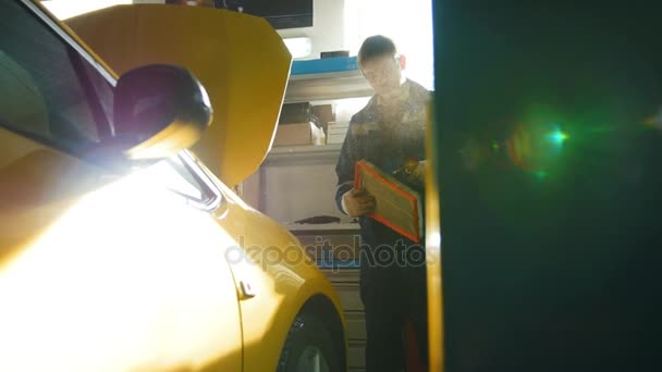 Mecánico del coche sopla filtro de aire del automóvil en taller de reparación, tiro deslizante — Vídeos de Stock