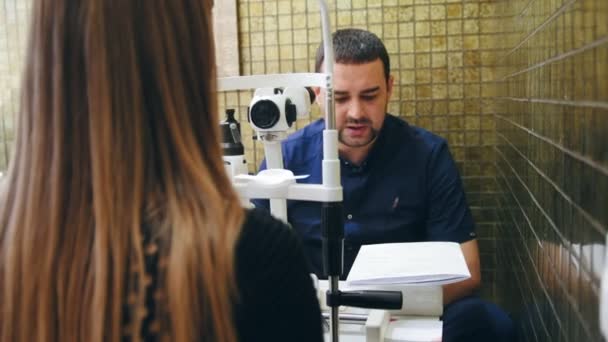 De dokter legt aan de vrouw patiënt zijn visie op Optometristen kamer - oftalmologie-concept — Stockvideo