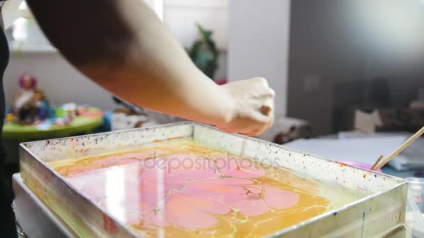 Malprozess - violette Farbtropfen auf gelbem Hintergrund - Frau zeichnet in flüssiger ebru-Technik auf Wasser — Stockvideo