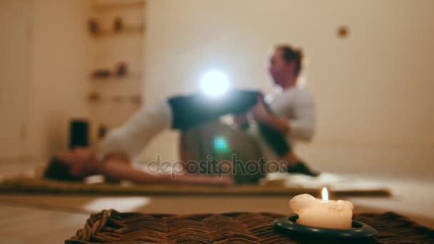 Desfocado - sessão de massagem em velas - tradicional tailândia alongamento para jovem modelo feminino — Vídeo de Stock