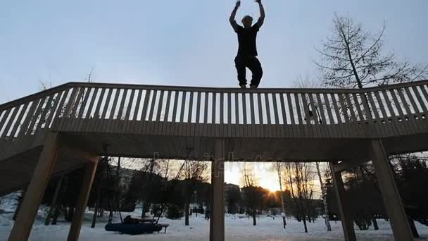 Αργή-mo άποψη της δωρεάν-run - ιχνηθέτη ξανθιά άνθρωπος δείχνει αναστροφή στο χειμερινό πάρκο στο ηλιοβασίλεμα, σιλουέτα — Αρχείο Βίντεο