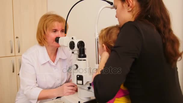 Mulher optometrista verifica a visão da menina - oftalmologia infantil — Vídeo de Stock