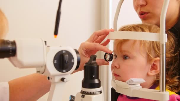 Childs ophthalmology - doctor optometrist checks eyesight at little girl — Stock Video