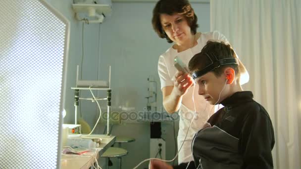 Gezondheid childrens diagnostische - optometrist zetten hersenen-eye apparatuur voor jongen patiënt - oftalmologie-kliniek — Stockvideo