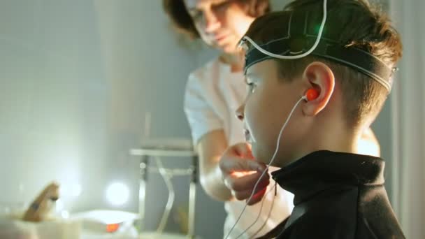 Mujer optometrista preparando adolescentes para la investigación de los ojos y el cerebro en la clínica de oftalmología — Vídeos de Stock