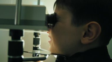 Çocuk genç görünümü kadar yakın gözleri vizyon yüksek teknoloji aygıtla denetler.